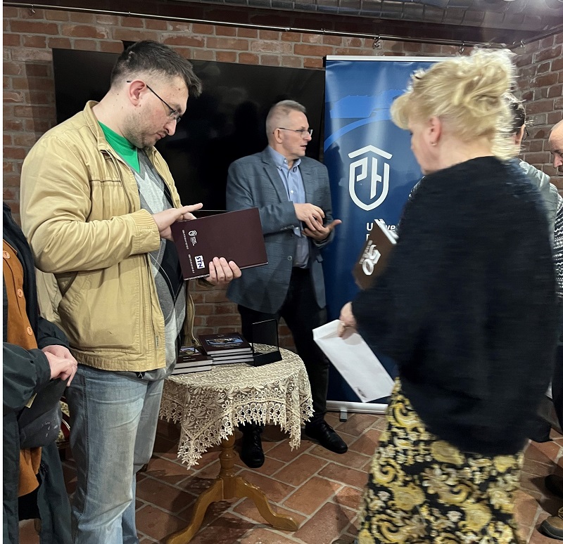 mezczyzna oglada ksiazke z prawej koieta w tle mezczyzna i aner